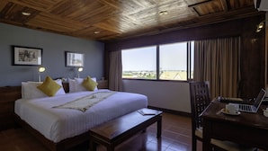 A hotel room with a large bed, a desk with a laptop, a view of the city, and wooden ceiling beams. - Pakse Hotel (Pakse)