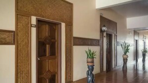 A hallway with a wooden door marked "501", potted plants, and a decorative statue. - Pakse Hotel (Pakse)