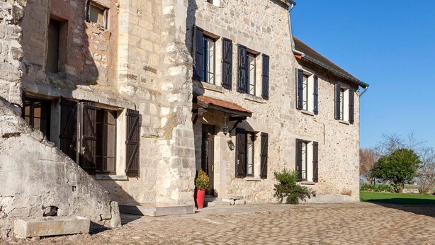 Un edificio histórico de piedra con varias ventanas y un patio empedrado.