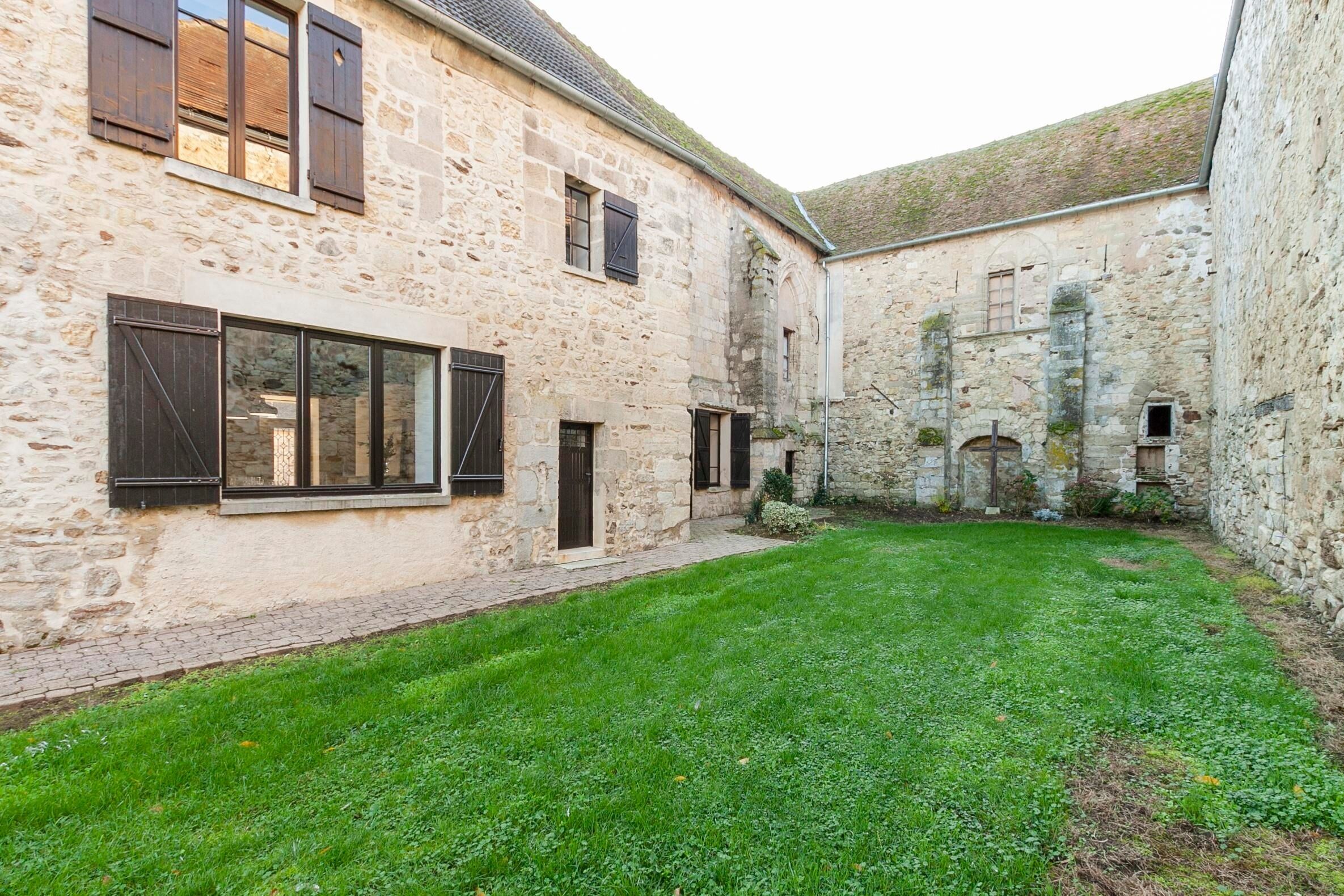 A courtyard with stone buildings, a grassy area, and a small garden.