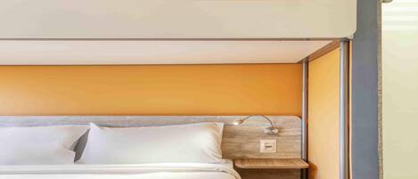 A bunk bed with a headboard, a bedside table, and a wall-mounted light fixture.