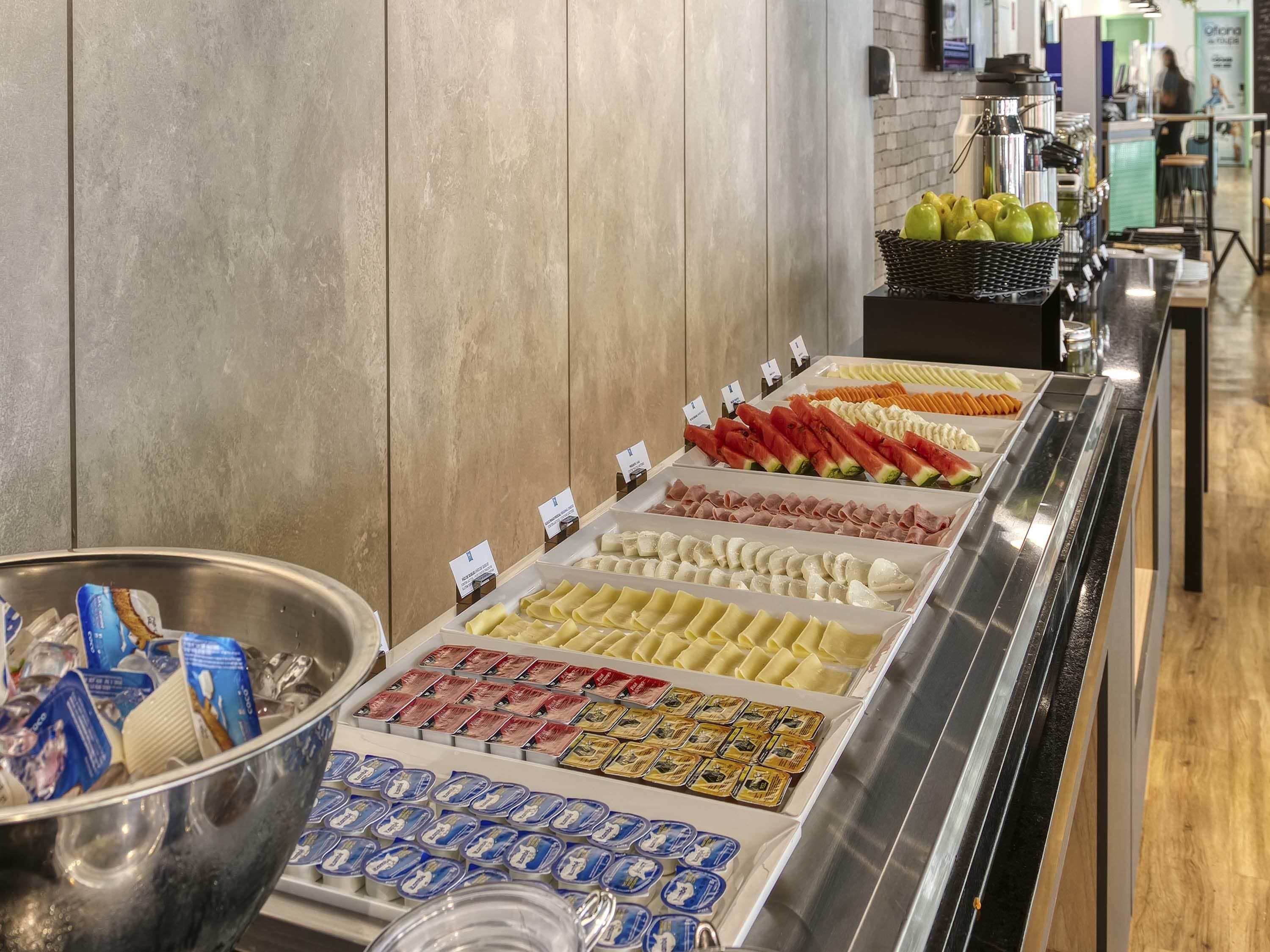 Um buffet com diversos alimentos, incluindo frutas, vegetais e lanches embalados.