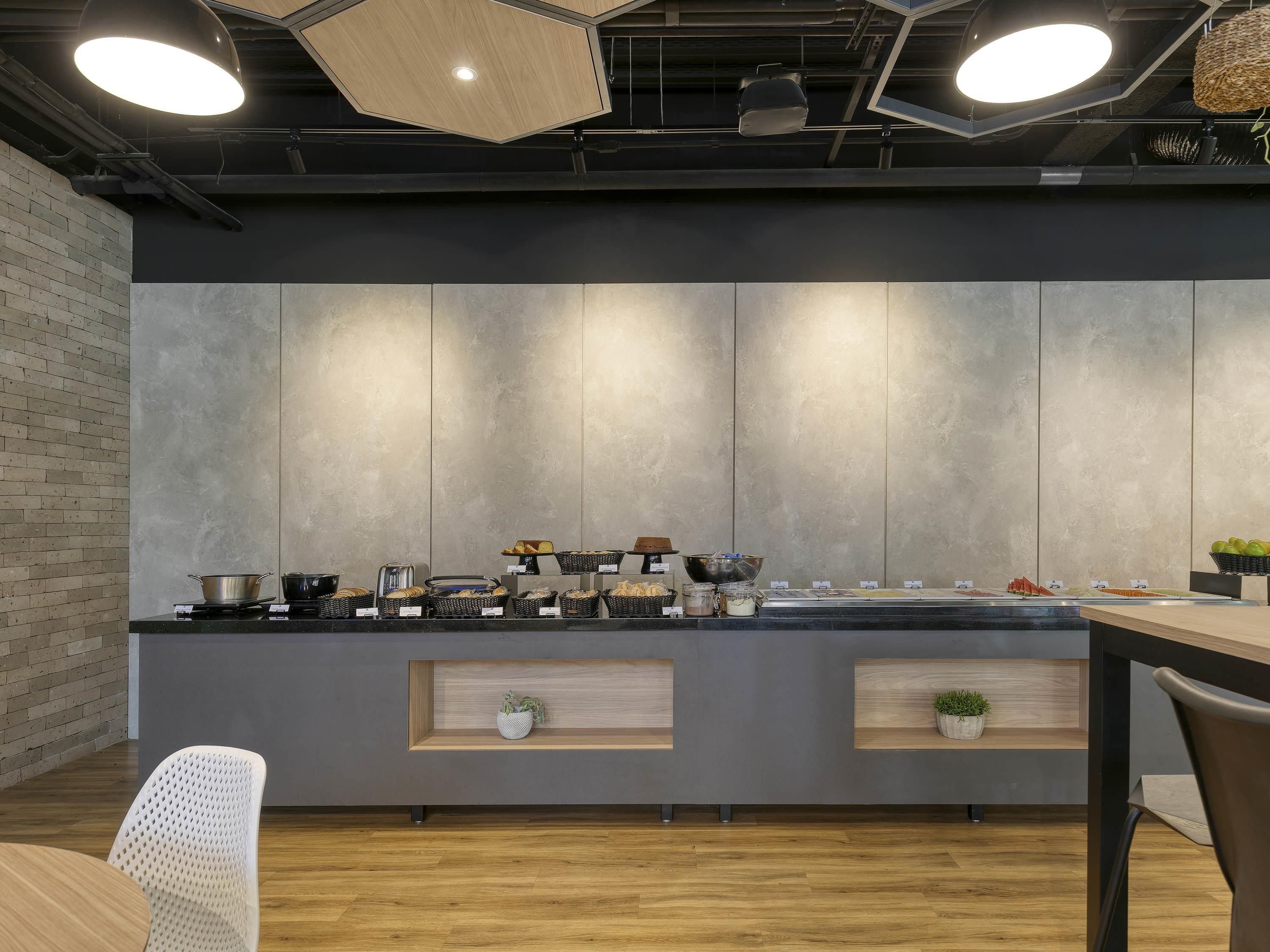 A modern kitchen with a central island, built-in appliances, and a brick accent wall.