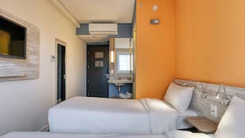 Quarto de hotel com duas camas, banheiro com pia e ar condicionado.