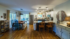 A spacious kitchen with a large island, wooden cabinets, and a vintage clock. - Southern Charm in Smoky Mountain Seclusion (Bryson City)