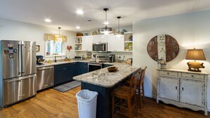 A modern kitchen with stainless steel appliances, a granite countertop, and a farmhouse-style clock. - Southern Charm in Smoky Mountain Seclusion (Bryson City)