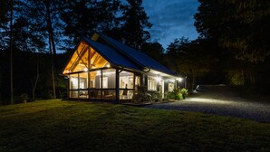 A cabin with a large porch, wooden exterior, and a sloped roof. - Southern Charm in Smoky Mountain Seclusion (Bryson City)