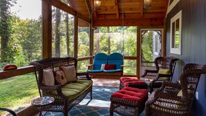 A covered porch with wicker furniture, large windows, and hanging lights. - Southern Charm in Smoky Mountain Seclusion (Bryson City)