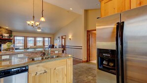 A modern kitchen with granite countertops, wooden cabinets, a stainless steel refrigerator, and a built-in dishwasher. - Pagosa Peak Mountain Views (Pagosa Springs)
