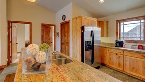 A kitchen with wooden cabinets, a stainless steel refrigerator, a granite countertop, and a window with a view. - Pagosa Peak Mountain Views (Pagosa Springs)