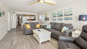 A spacious living room with a grey sofa set, a white coffee table, and a ceiling fan. - Show-stopping views at this oceanfront condo w/indoor & outdoor pools, lazy river, kids' pool (North Myrtle Beach)