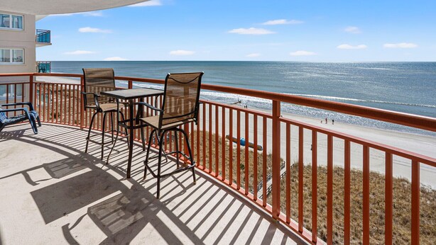 A balcony with a table and chairs, overlooking a beach and the ocean. - Show-stopping views at this oceanfront condo w/indoor & outdoor pools, lazy river, kids' pool (North Myrtle Beach)