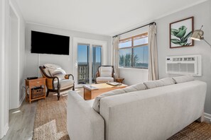 A modern living room with a sofa, two armchairs, a coffee table, a TV, and a window with curtains. - Amazing views, newly remodeled luxury oceanfront condo w/private balcony and pool (North Myrtle Beach)
