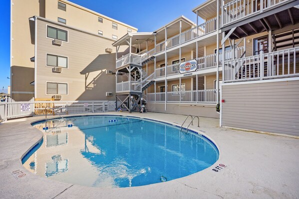 A swimming pool with a multi-level balcony, a lifeguard tower, and a sign indicating no lifeguards on duty. - Amazing views, newly remodeled luxury oceanfront condo w/private balcony and pool (North Myrtle Beach)