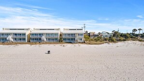 Et hotel ved stranden med flere etager, en sandstrand foran og en klar himmel.