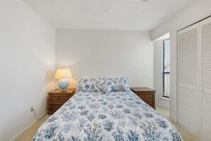 A bedroom with a bed, nightstands, a lamp, and a closet. - Beachfront Condo! West End PCB - Steps to the beach! Harbor Arms #6 - Dog Friendly (Panama City Beach)