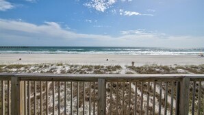 A beach with a wooden boardwalk leading to the shore, sandy beach, and ocean waves.