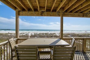 Enjoy a serene ocean view from this deck with a table and chairs, overlooking the beach and a pier.