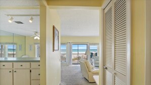 Hotelkamer met een grote spiegel, een kitchenette, een balkon met uitzicht op het strand en een zithoek met een bank en stoelen.