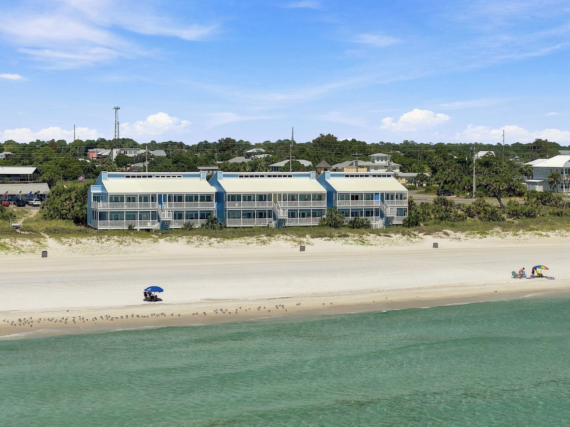 Een strandhotel met meerdere gebouwen, een zandstrand en een helder uitzicht op de oceaan.