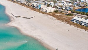 Luchtbeeld van een kustplaats met strandwoningen en een helder uitzicht op de oceaan.