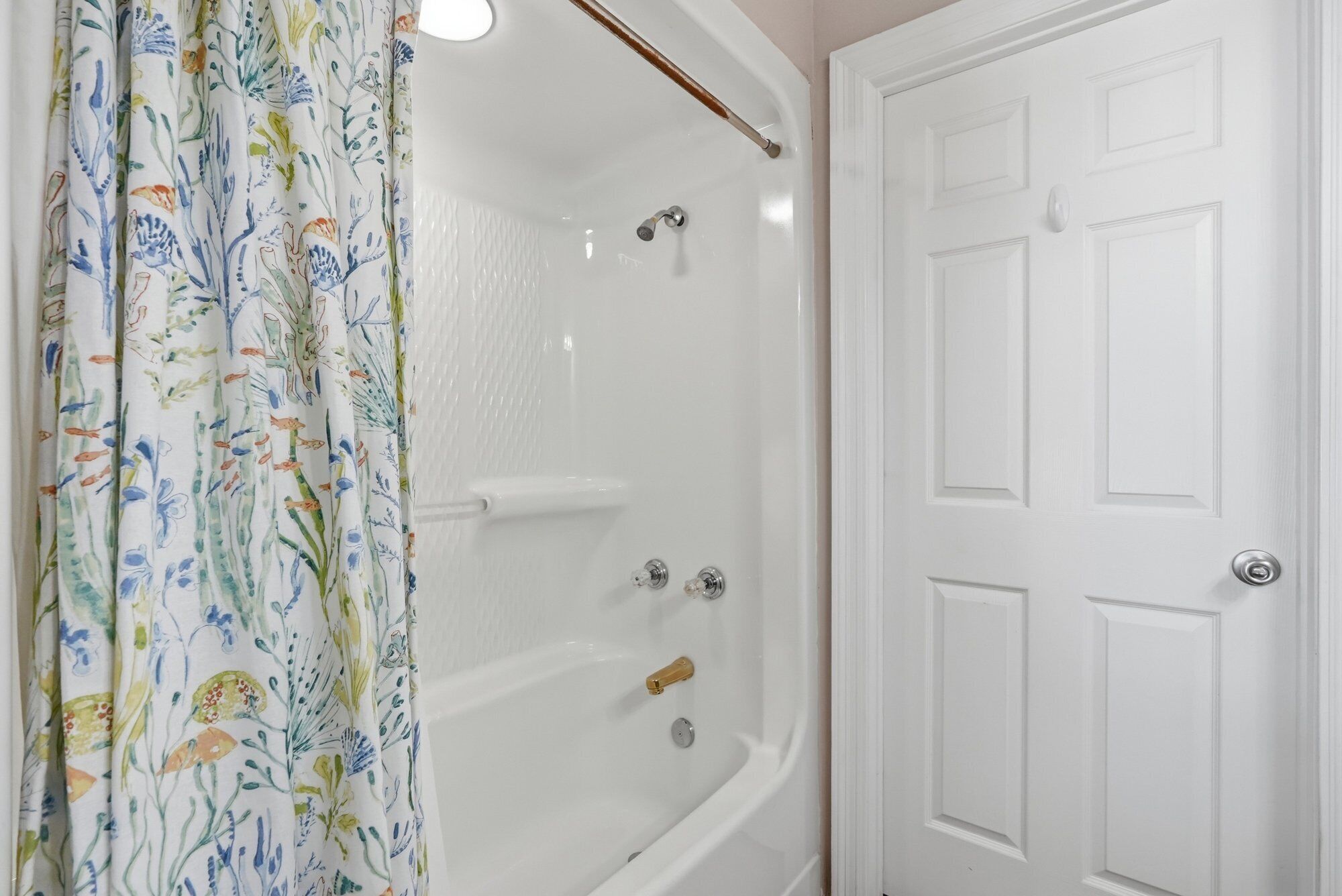 A bathroom with a shower, a bathtub, and a white door.