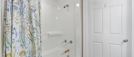 A bathroom with a shower, a bathtub, and a white door.