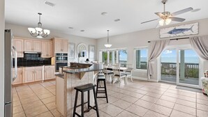 A spacious kitchen with a central island, a dining area with a view, and a ceiling fan.