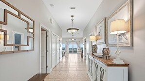 A hallway with a bench, a console table with decorative items, and framed artwork on the walls.