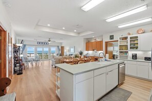 Una cocina moderna con armarios blancos, una isla central y vistas al océano.