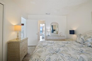 Cozy retreat with a large bed, wicker side table, and dresser, perfect for a restful stay.