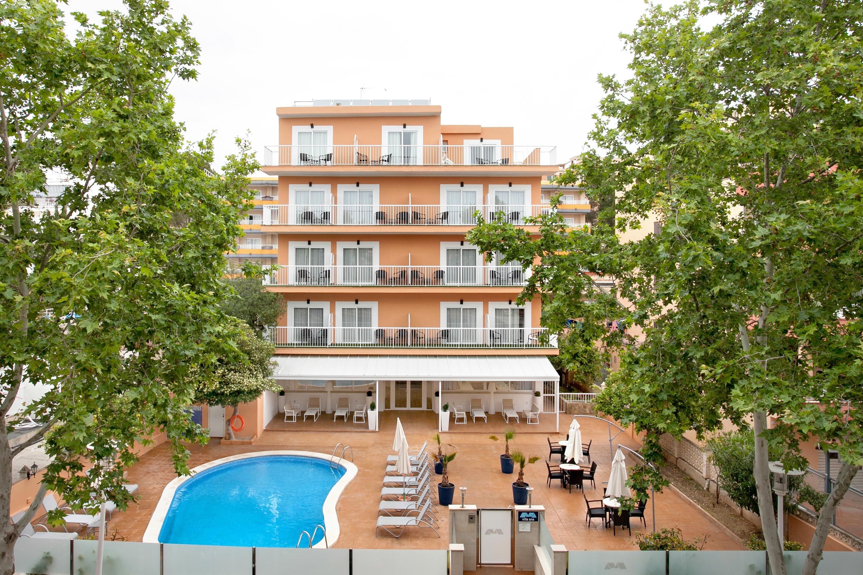 A multi-story hotel with a swimming pool, outdoor seating, and balconies.