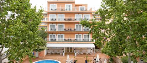 A multi-story hotel with a swimming pool, outdoor seating, and balconies.