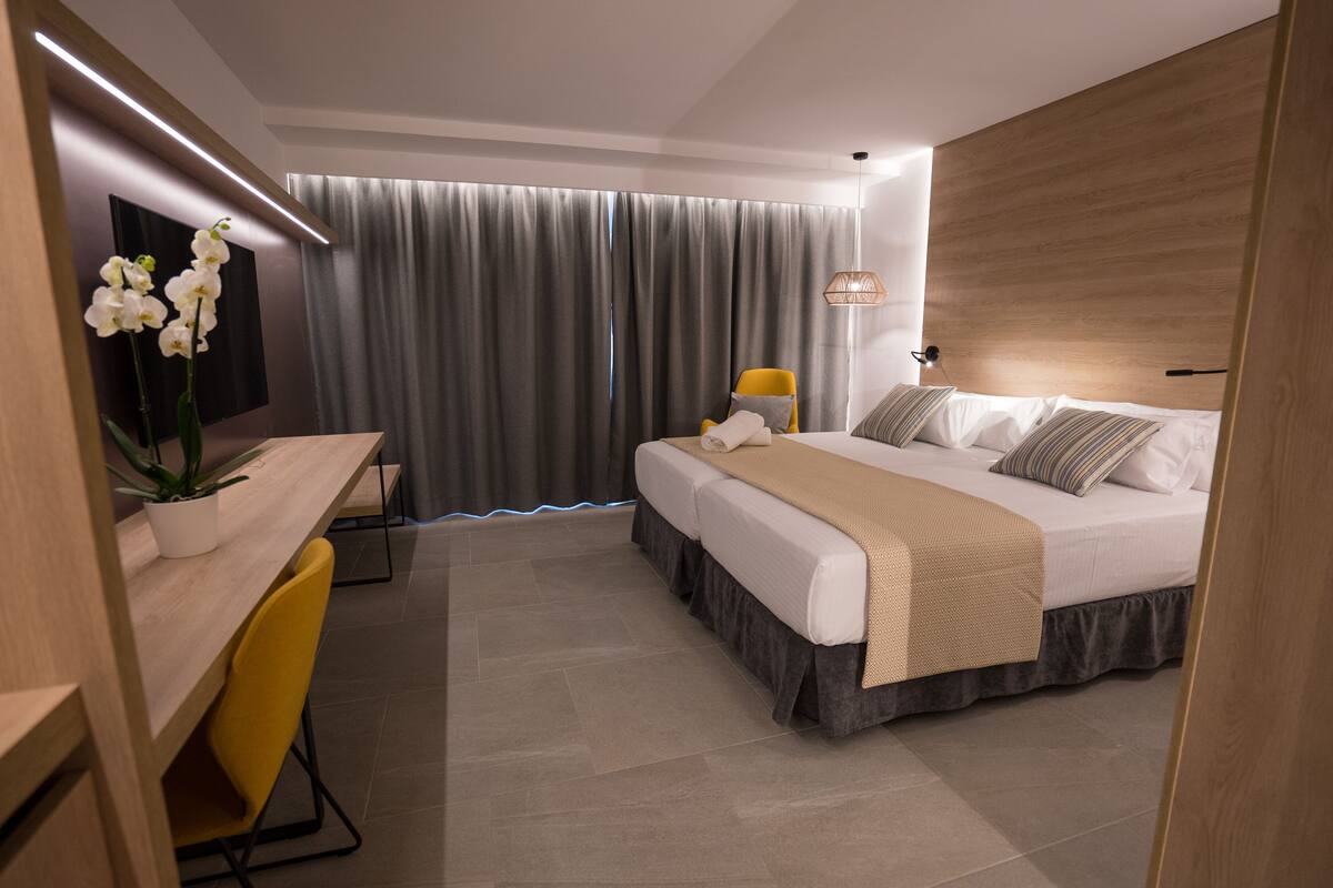 A modern hotel room with a bed, a desk, and a chair.