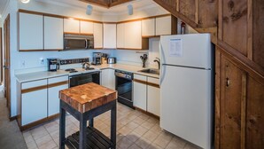 A compact kitchen with white cabinets, a microwave, a stove, a sink, and a refrigerator. - Whiffletree A7 (Killington)