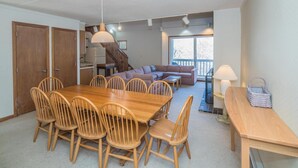 A spacious living area with a wooden dining table and chairs, a sofa, and a staircase leading to a loft. - Whiffletree A7 (Killington)