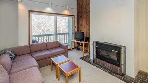 A cozy living room with a sectional sofa, a fireplace, and a television on a wooden table. - Whiffletree A7 (Killington)