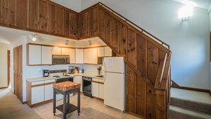 A kitchen with wooden cabinets, a microwave, a stove, a sink, and a refrigerator. - Whiffletree A7 (Killington)
