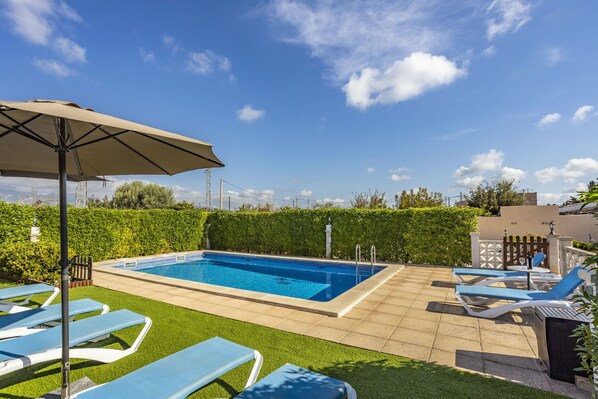 Relax by the pool surrounded by lush greenery and comfortable lounge chairs.
