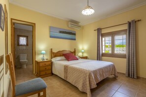 Enjoy a restful stay in this cozy room with a neatly made bed, bedside tables, and a window with a view of the landscaped area.
