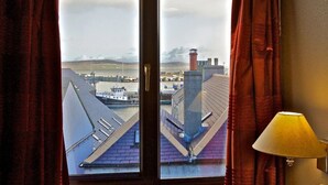 A window with a view of a harbor, including buildings and a boat. - The Royal Hotel Stromness (Stromness)