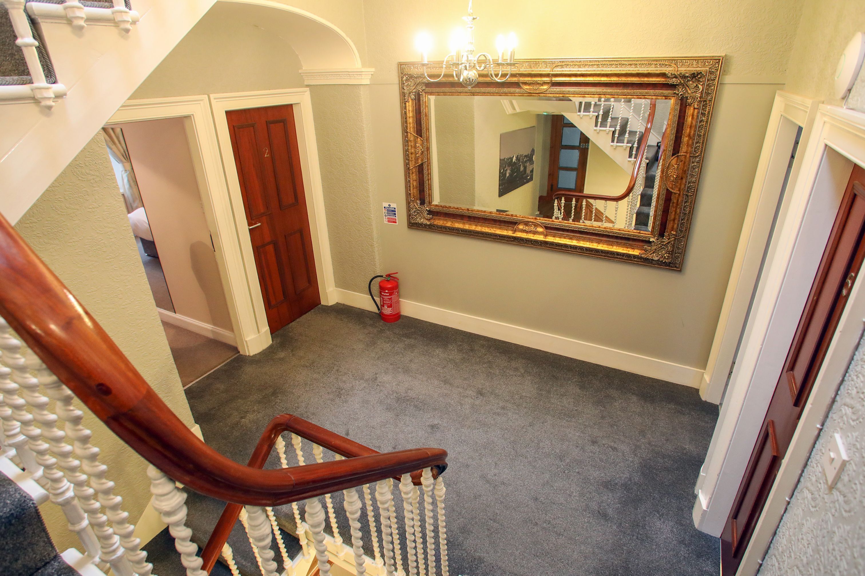 A staircase with a wooden handrail and a mirror on the wall.