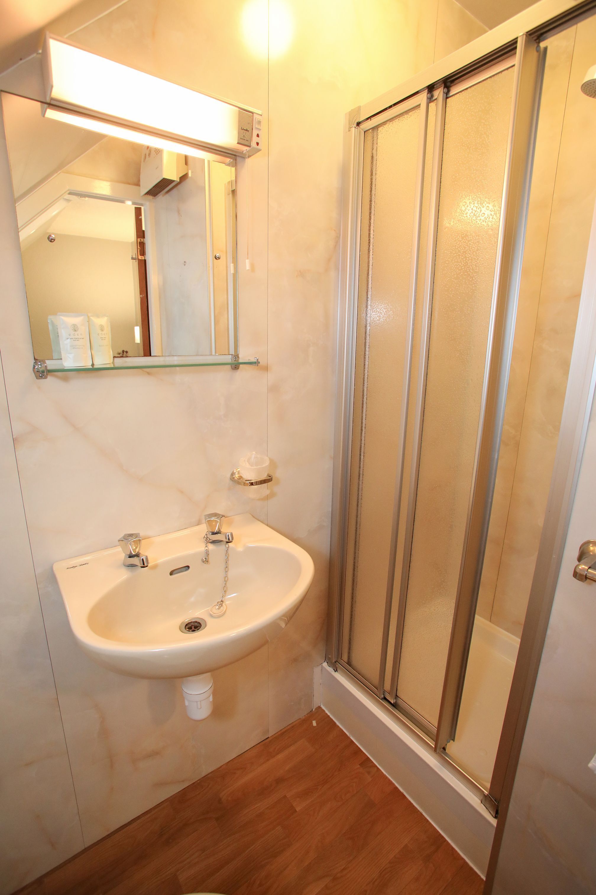 A bathroom with a sink, mirror, and shower.
