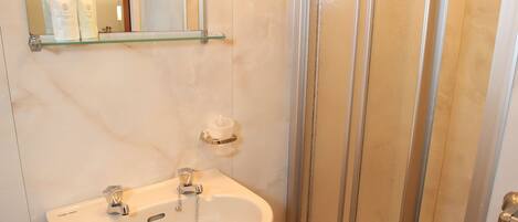Un baño con lavamanos, espejo y ducha.
