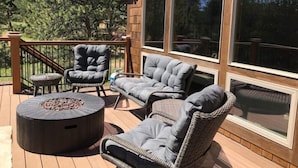 A wooden deck with wicker furniture, a round table, and a fire pit. - 4 bedrooms 3 bath close to downtown and RMNP- beautiful! (Estes Park)