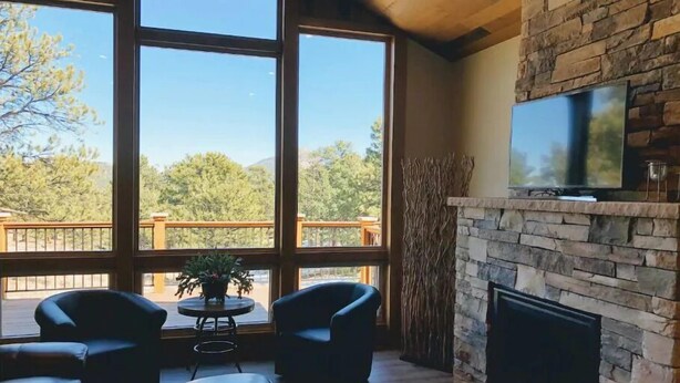 A spacious living room with large windows, a stone fireplace, and a flat-screen TV. - 4 bedrooms 3 bath close to downtown and RMNP- beautiful! (Estes Park)