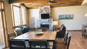 A spacious dining area with a wooden table and chairs, a stone fireplace, and a ceiling fan. - 4 bedrooms 3 bath close to downtown and RMNP- beautiful! (Estes Park)