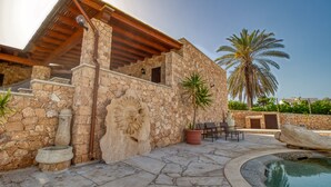 A stone building with a pool, outdoor seating, and palm trees. - Il Corallo - Bilo 2 IV (Lampedusa)
