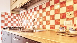A kitchen with a checkered backsplash, stainless steel sink, and a stove. - Il Corallo - Bilo 2 IV (Lampedusa)
