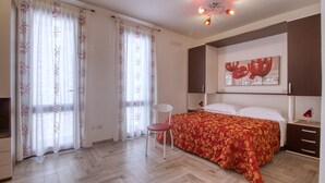 Un dormitorio con una cama, una silla, una mesita de noche y un cuadro en la pared.